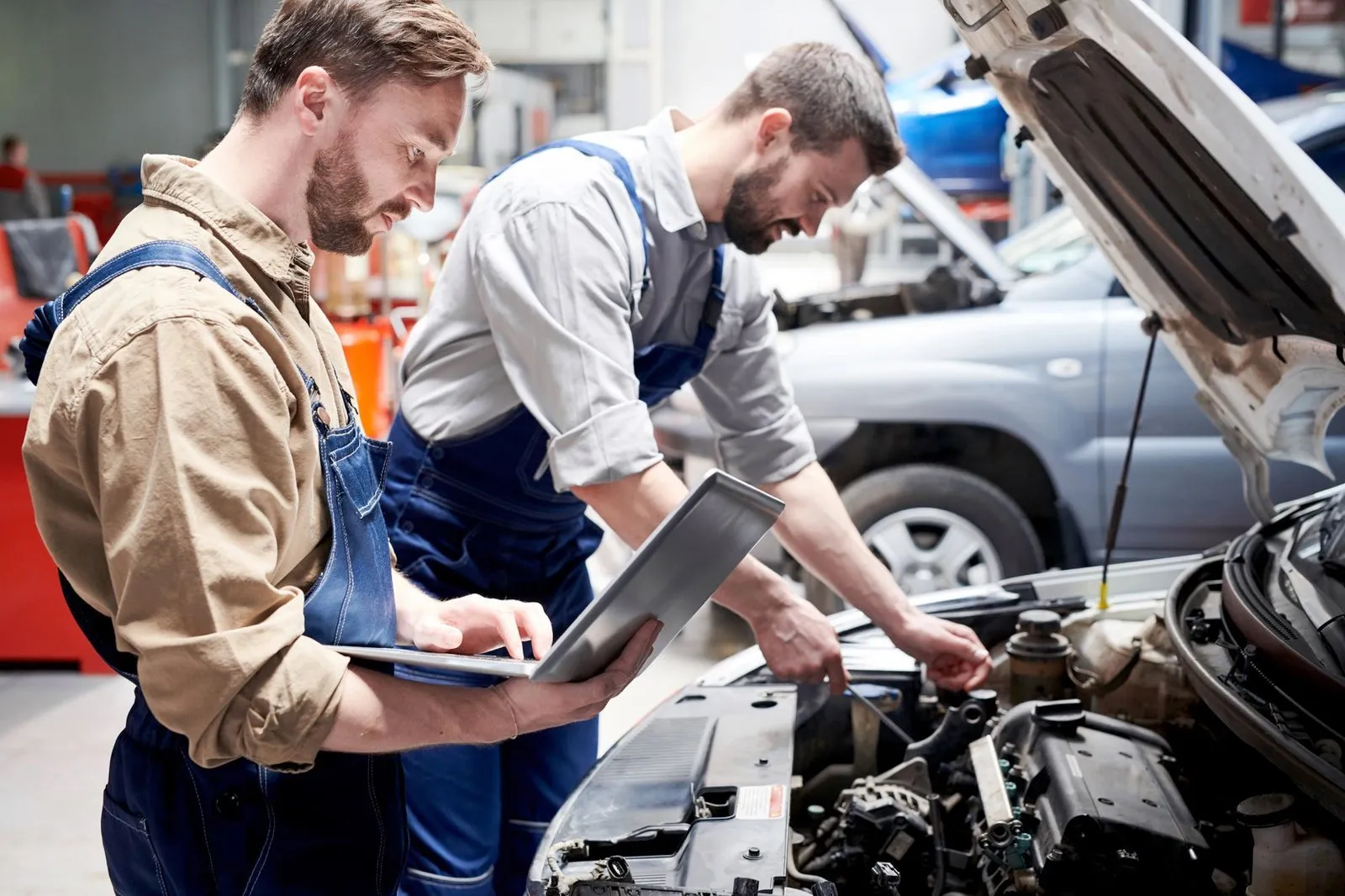 Two mechanics working on a car in a garage