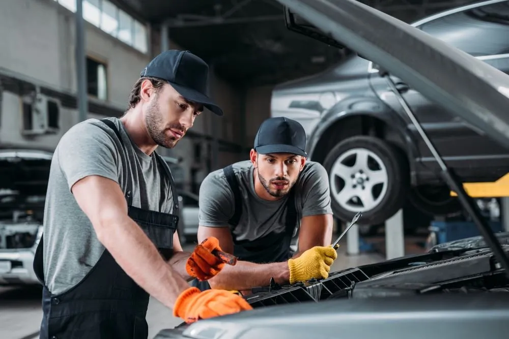 Two mechanics working under a car bonnet